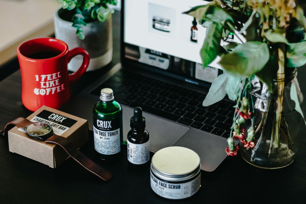 Hudvårdsprodukter och en kaffemugg framför en bärbar dator som visar en webbutik